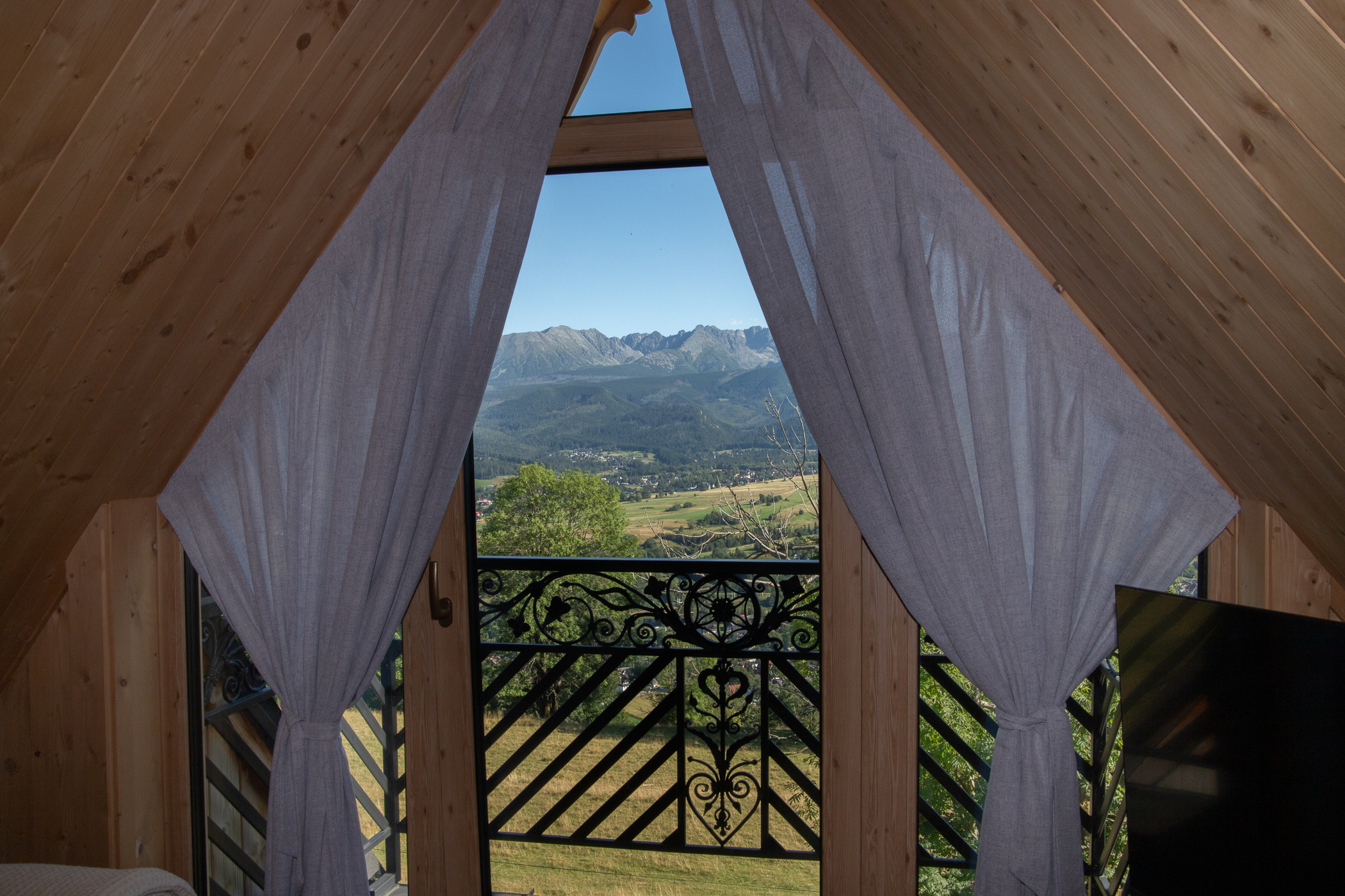 Drewniany taras z krzesłami, stolikiem i widokiem na Tatry